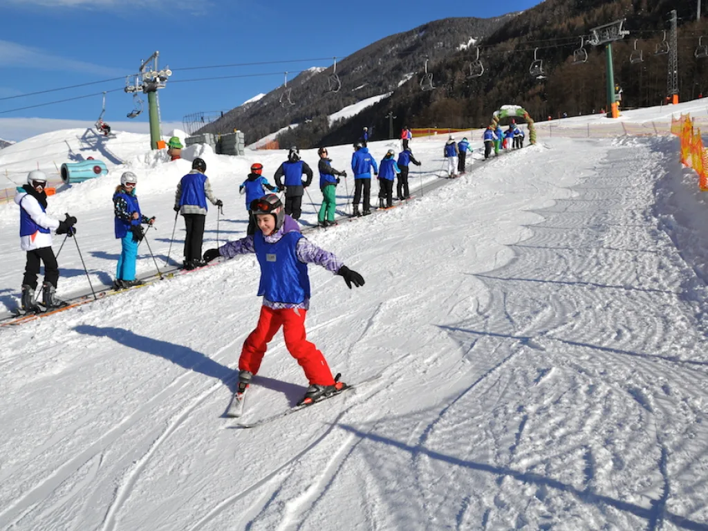 Skifahrerin in rotem Anzug fährt auf die Kamera zu.